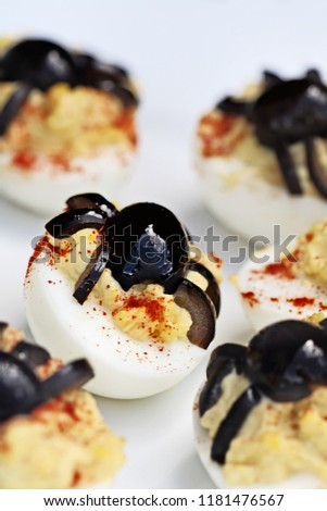 Fun food for kids. Halloween boiled eggs with black olive spiders on top of them. Extreme shallow depth of field with selective focus on center egg. Alternative to candy.