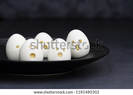 Fun food for kids. Hard boiled ghost ghoul eggs perfect for Halloween parties. Alternative to candy. Shallow depth of field with selective focus on egg in front of plate.