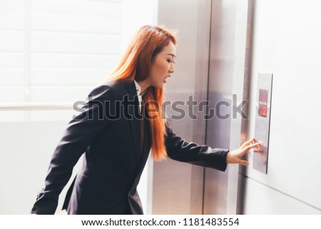 Young Asian businesswoman in hurry rush hour pressing an elevator button