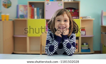 Kindergarten. The child shows different emotions. The girl is 5-6 years old with blond hair. The child is very emotional, shows sadness and joy in the children's playroom. Childhood education concept.