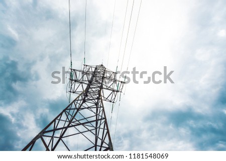Electricity distribution tower with copy space. High voltage power lines under cloudy sky. Minimalist view from below on poles with wires at overcast weather. Atmospheric electrical background.