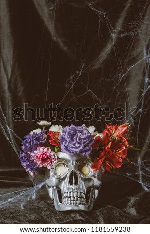 silver halloween skull with flowers on dark cloth with spider web 