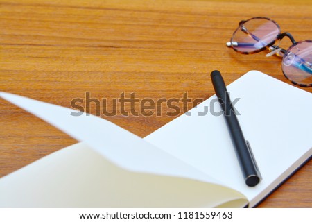 Skecthing book or notebook with pen and glasses on my wooden table