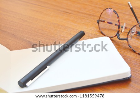 Skecthing book or notebook with pen and glasses on my wooden table