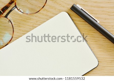 Notebook,pen and glasses on wooden background in the office. Space for text