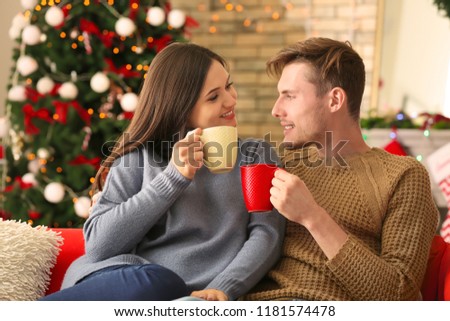 Cute young couple drinking hot chocolate at home on Christmas eve