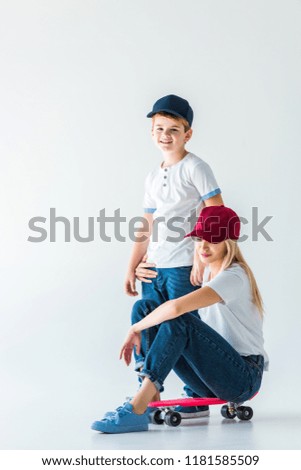 mother sitting on skate and hugging son on white