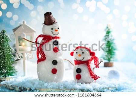 A festive winter background with two happy snowmen made from balls of yarn, buttons and lace. Christmas card, copy space.