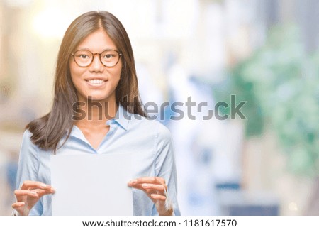 Young asian woman over isolated background holding blank paper with a happy face standing and smiling with a confident smile showing teeth