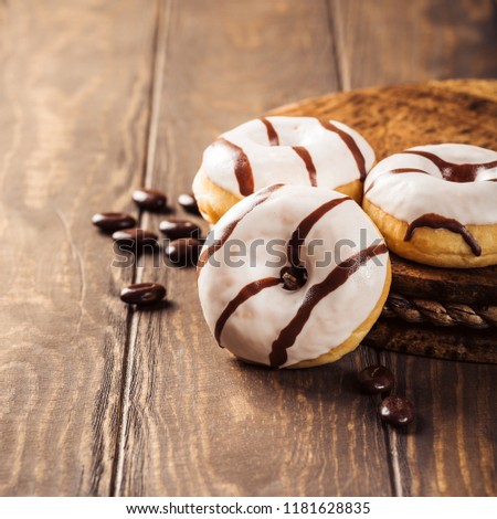 Glazed mini donuts with coffee candies on wooden background. Party food concept with copy space.