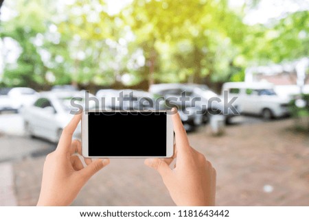 woman use mobile phone and blurred image of the car park in the garden
