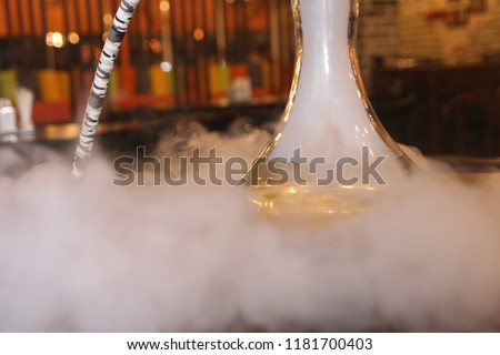 Thick white smoke hookah on the table in a cafe