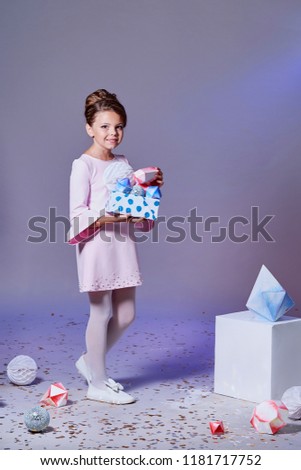 Lady little girl in beautiful pink dress with gift present box. Fashion child model.Holidays, christmas, new year, x-mas concept. Full length kid posing in studio, isolated pink background.