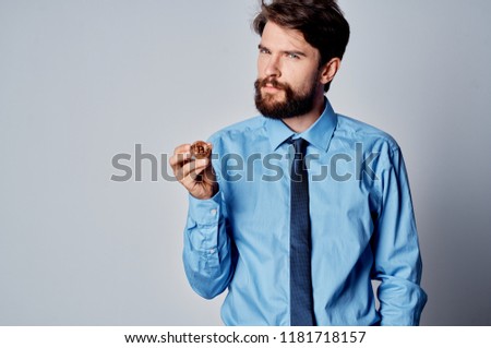 a man in a blue shirt with a tie is holding a Bitcoin crypto currency                           