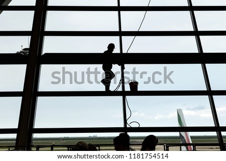 Silhouette shot of glass cleaning by spiderman worker in the airport.