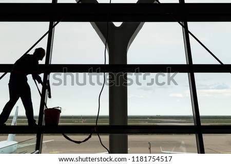 Silhouette shot of glass cleaning by spiderman worker in the airport.