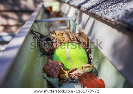 Tennis ball stuck in gutter on a roof Royalty-Free Stock Photo #1181779972