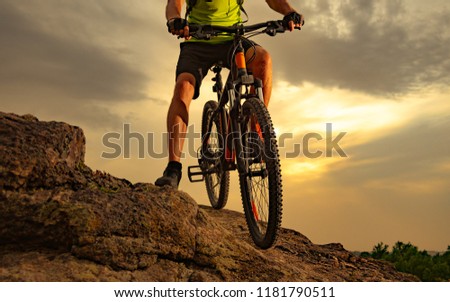 Enduro Cyclist Riding the Mountain Bike on the Rocky Trail at Sunset. Close-up of Bicycle. Active Lifestyle Concept.