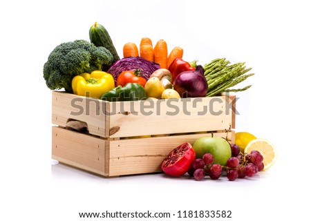 Pine box full of colorful fresh vegetables and fruits on a white background, ideal for a balanced diet, contains broccoli, cucumber, onion, asparagus, peppers, carrots, apple, grape, lima and potatoes Royalty-Free Stock Photo #1181833582
