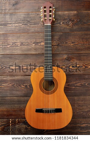 Acoustc guitar on brown wooden background. Ukulele on textured wooden surface, vertical image.