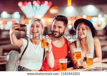 Group of friends drinking beer and taking selfie at music festival
