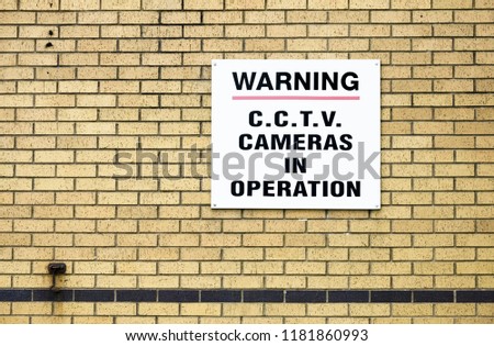 CCTV camera in operation sign on brick wall