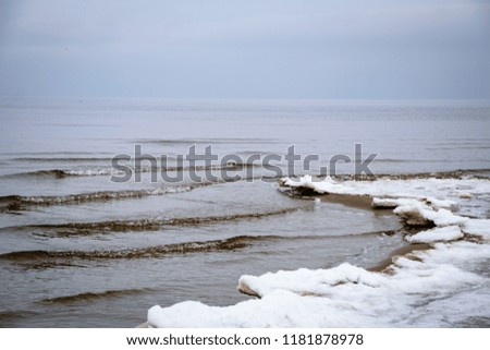 frozen dunes by the sea with ice water and snow on the beach sand