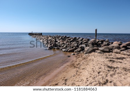 old stone brakewater in hte Baltic seawith blue sky and calm water