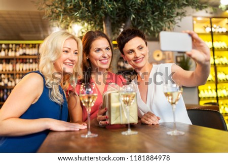 technology, celebration and birthday concept - happy women with gift taking selfie at wine bar or restaurant