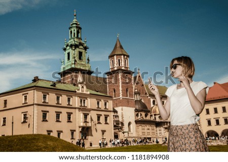 A young woman with a mobile phone in the courtyard . Taking pictures by phone. A stylish girl at historic building. Ancient architecture.