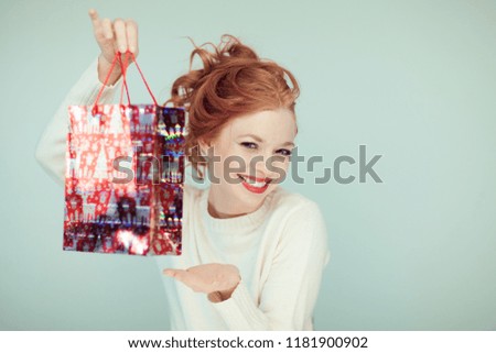 Beautiful woman with red curly hair holds a christmas gift in her hands, can be used as background