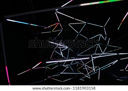 Indoor view of fluorescent neons in a dark dance hall. Pattern of white lines making polygonal shapes with a black background. Modern abstract design with drawings created by illuminated long lamps.