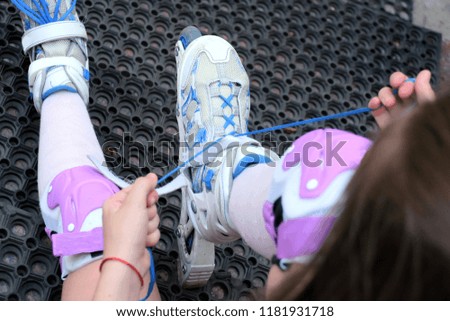 Girl on blue roller, tires shoelaces before roller skating