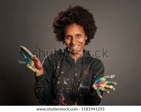 happy black woman with her hands painted on a gray background