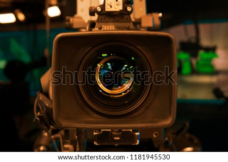 Television Film Camera with focus on the rim of the lens. On Air Broadcast sign in the background.