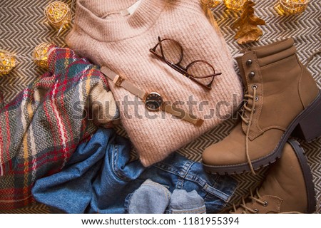 Autumn clothing outfit with sweater, jeans and boots, top view of fall/winter season outfit idea with glasses and watch accessory