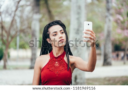 Selfie portrait of a positive young woman outside in the park