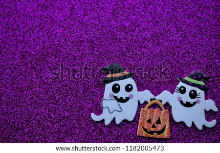two ghosts holding a pumpkin bag on purple background