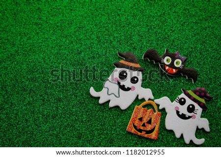 two ghosts holding a pumpkin candy bag with a bat flying over head on a green background