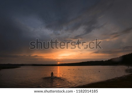 beautiful sunset sky with colorful clouds reflected in the water, the Golden hour for landscape photography, the lake in calm weather, warm and want to swim, entering the water from the shore, silence
