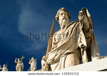 Apostle Paul statue in front of St Peter's Basilica, Rome, Italy. Beautiful Baroque monument on blue sky background. Roman sculpture of Saint Paul with sword at San Pietro facade in Vatican City. 