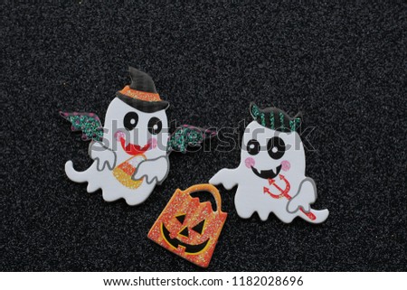 two ghosts holding a pumpkin trick or treat bag on a black background