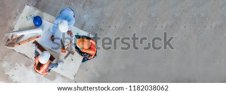 Team of young man and woman engineer and architects working, meeting, discussing,designing, planing, measuring layout of building blueprints in construction site floor at factory.top view & copy space Royalty-Free Stock Photo #1182038062
