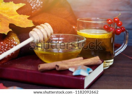 cosy autumn composition with cup of tea, honey, maple leaves, woolen scarf on dark brown background. autumn, fall concept