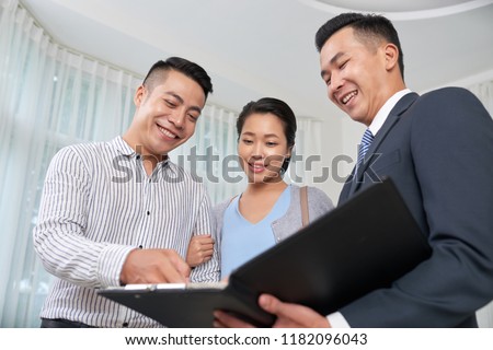 Cheerful real estate agent showing photos of objects to clients