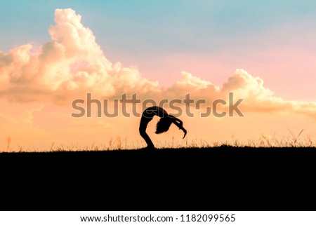 silhouette of children playing yoga on meadow at sunset time