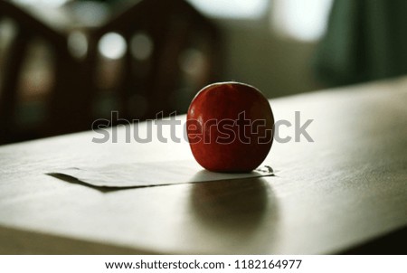 Silhouette of red apple and piece of paper closeup on table interior blur background