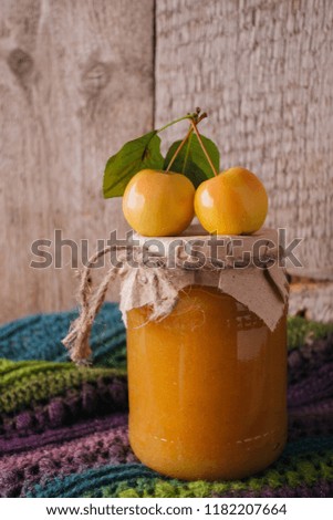 Homemade apple jam in bank in the autumn background with ripe apples and green leaves on the old wooden table