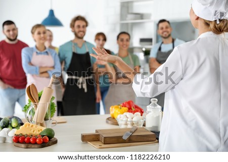 Group of people and female chef at cooking classes Royalty-Free Stock Photo #1182226210
