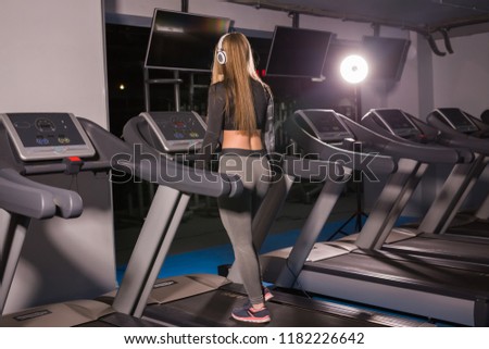 Young sports woman is working out in gym. Doing cardio training on treadmill.
